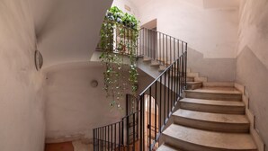 A spiral staircase with a metal railing and a plant-covered landing.