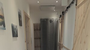 Un pasillo con piso de madera, una puerta corredera tipo granero y una puerta con persianas verticales.