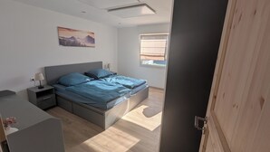 Un dormitorio moderno con una cama, mesitas de noche, una ventana con persianas y un cuadro en la pared.