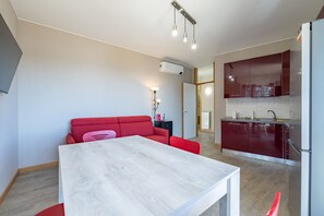 A modern apartment with a dining area, a kitchenette, and a red sofa. - Sole Mare by Wonderful Italy (Sanremo)