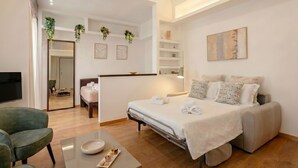 Habitació d'hotel amb un llit, una taula de treball, una cadira, un televisor i un mirall.