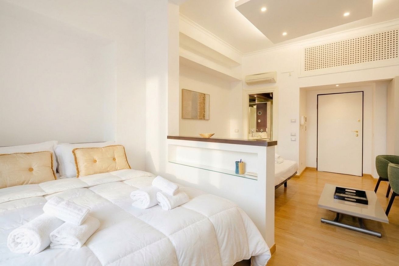Une chambre d’hôtel avec un lit, un bureau, une chaise, un miroir et une porte.