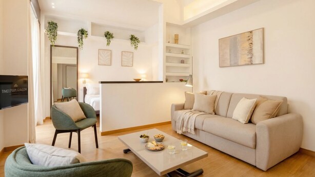 A modern living room with a sofa, armchairs, a coffee table, and a TV.