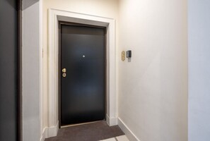 A closed door with a brass handle and a small, rectangular intercom device on the wall beside it. - Mercantile 76 - Elegant Loft in the Historic Center (Bari)