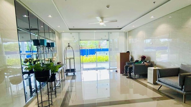A spacious lobby with a modern design, featuring a seating area with a sofa and chairs, a reception desk, and a glass partition with potted plants. - SMDC Park Residences Condo unit 417 near SM City of Santa Rosa Laguna (City of Santa Rosa)