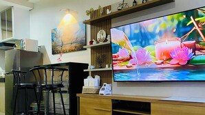 A modern living room with a large flat-screen TV, wooden entertainment unit, black chairs, and a small potted plant. - SMDC Park Residences Condo unit 417 near SM City of Santa Rosa Laguna (City of Santa Rosa)