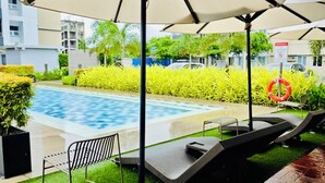 An outdoor swimming pool area with lounge chairs and umbrellas. - SMDC Park Residences Condo unit 417 near SM City of Santa Rosa Laguna (City of Santa Rosa)