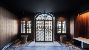 A hallway with a large arched door with intricate metalwork, flanked by two trash bins and a bench. - Ca Dadda terrace at Rialto Bridge -historic residence equipped with all comforts (Venezia)