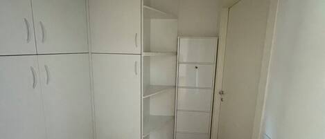 A narrow hallway with white closets and a door.