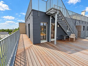 Ein modernes Gebäude mit einer Holzterrasse, einer Treppe und einem Stuhl.
