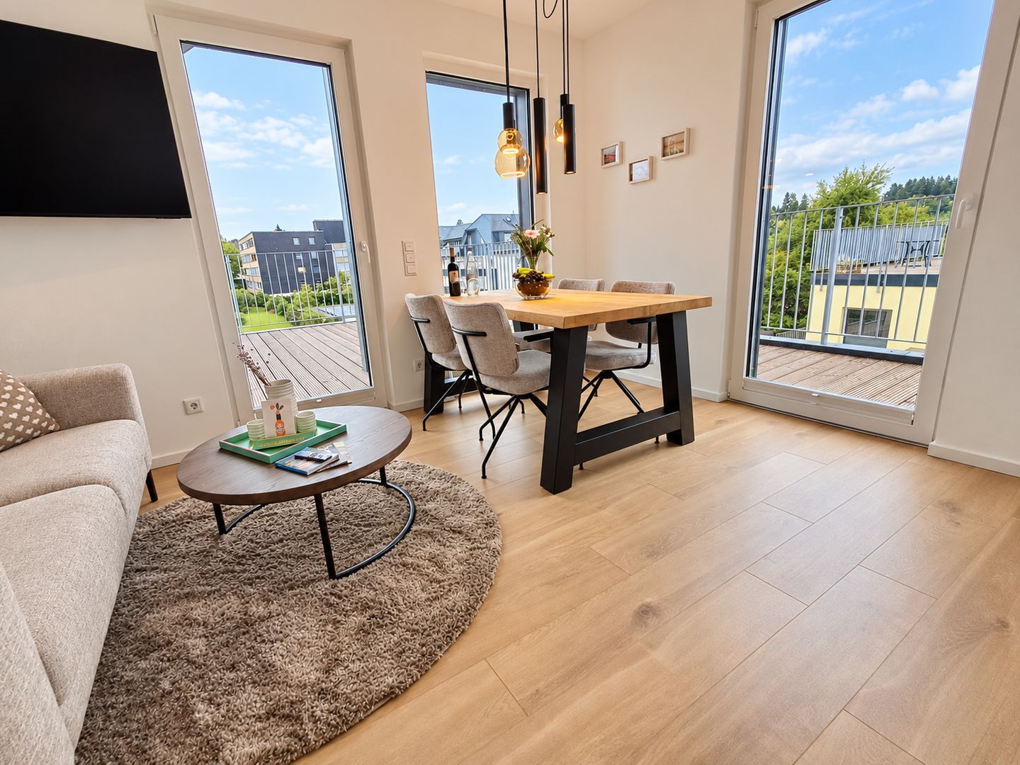 A modern living room with a round coffee table, a sofa, and a dining area with a wooden table and chairs.