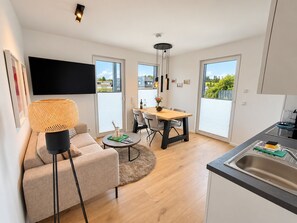 A modern apartment with a dining area, kitchen, and living space.