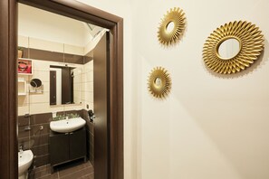 Un baño con lavamanos, espejo y dos espejos decorativos en la pared.