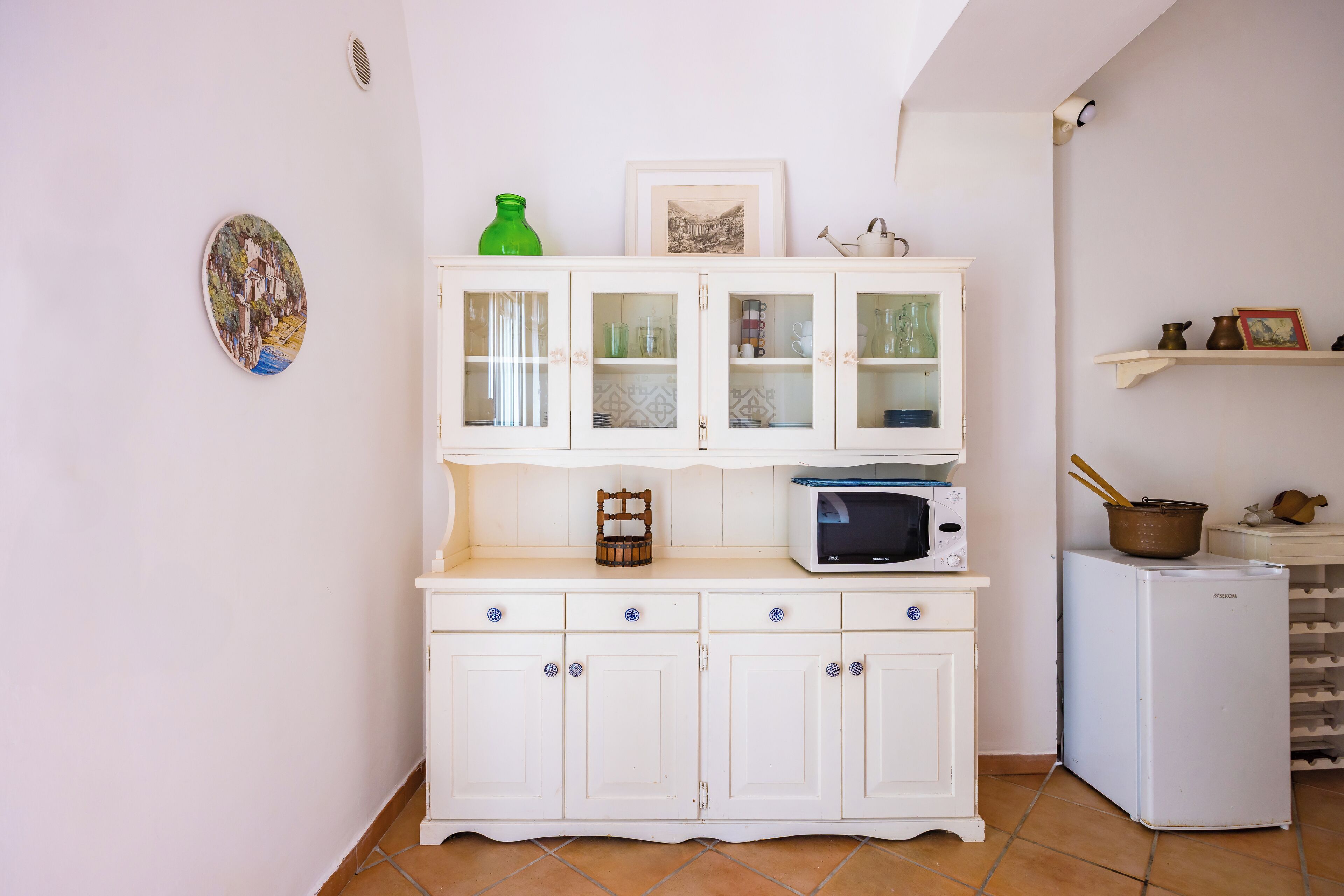 Una cocina con armarios blancos, microondas y refrigerador.