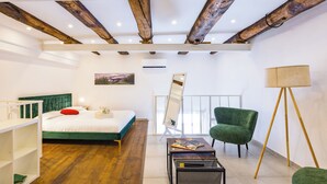 Un dormitorio con una cama, un sillón verde, una lámpara de pie y un cuadro en la pared.