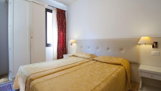 A hotel room with a bed, bedside lamps, a nightstand, and a door. - albergo ai Tolentini (Venice)