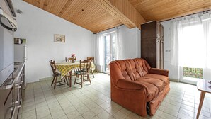 A cozy living room with a wooden ceiling, a brown sofa, a dining table with chairs, and a kitchen area with cabinets. - Amazing home in Rogoznica with WiFi (Rogoznica)