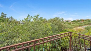 A balcony with a metal railing overlooking a lush garden and a residential area with houses in the background. - Amazing home in Rogoznica with WiFi (Rogoznica)