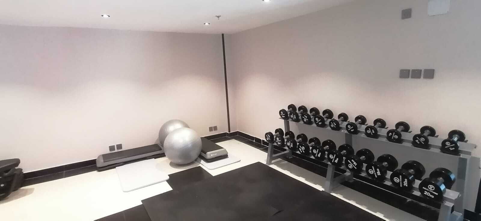 A gym with exercise equipment, including dumbbells and a medicine ball.