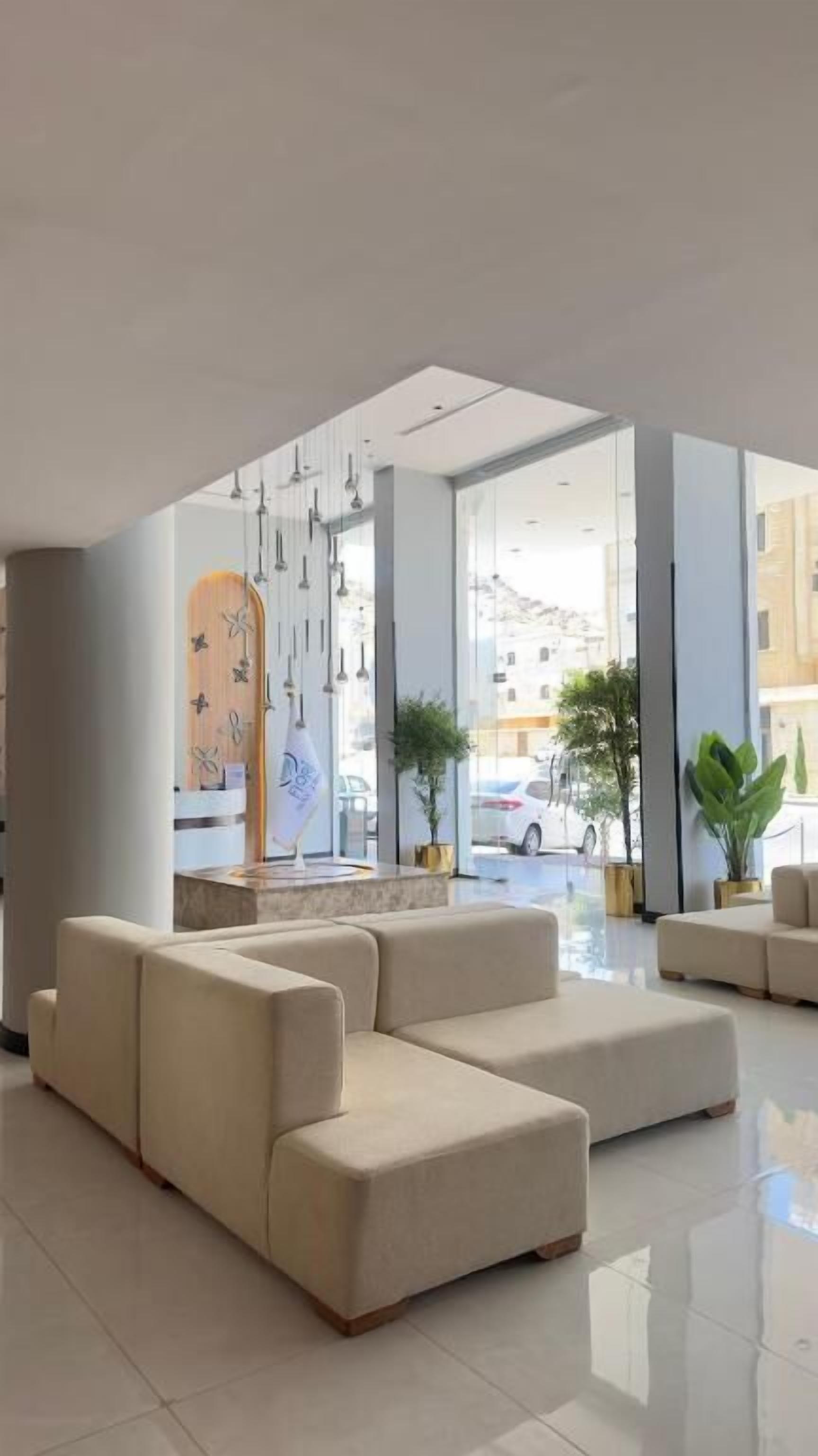 Un vestíbulo moderno con área de descanso, ventanas amplias y lámparas colgantes.