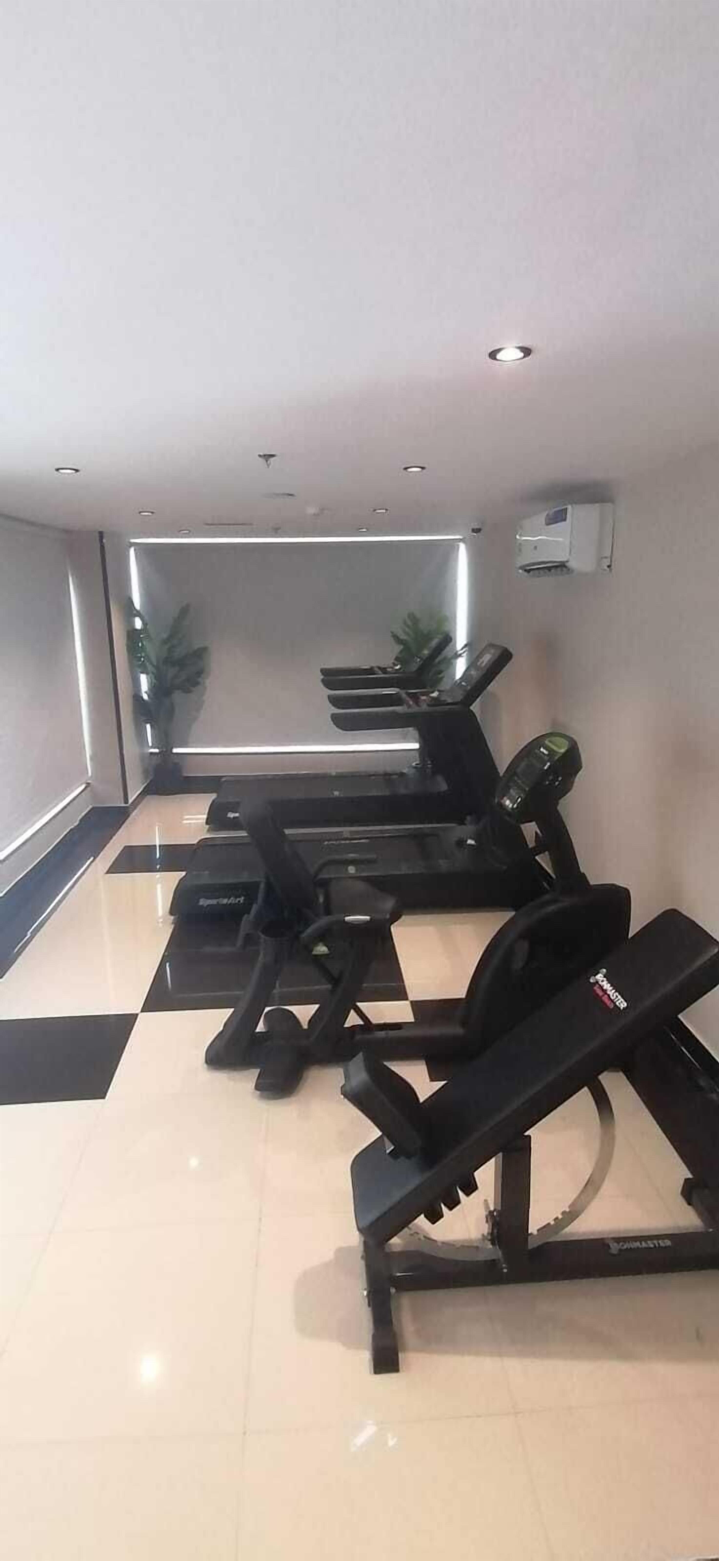 A gym with multiple treadmills and a bench.