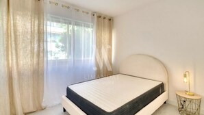 A bedroom with a bed, curtains, a window, and a bedside lamp.
