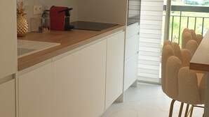 A modern kitchen with white cabinets, a wooden countertop, and a red chair.