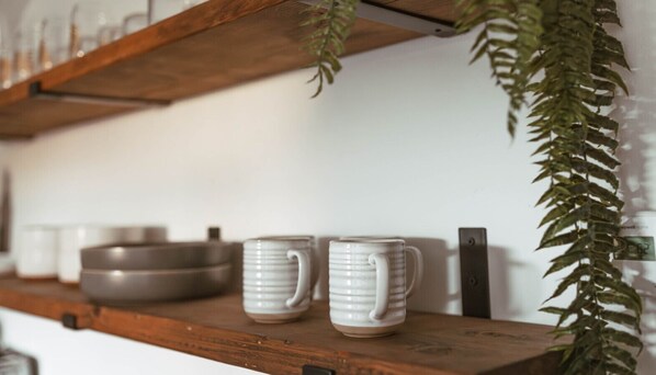 Una estantería con tazas de cerámica y un cuenco.