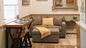 A cozy room with a wooden table, a cushioned sofa, and a large mirror.
