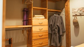 A wooden wardrobe with multiple drawers and a hanging robe.