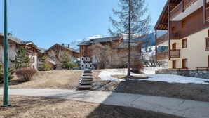 Un hôtel doté de nombreux balcons, d’une façade en pierre et offrant une vue sur des montagnes enneigées.