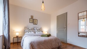 Ein Schlafzimmer mit Bett, Nachttischen, einem Spiegel und einer Tür.