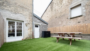 Ein Garten mit einem Holztisch, einer Steinmauer und einer Tür.