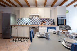 Una cocina con gabinetes blancos, salpicadero a cuadros, refrigerador, lavavajillas y un menú en pizarra.