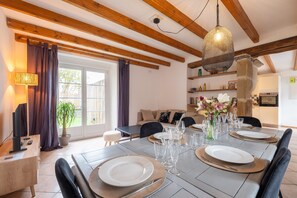Een eethoek met een tafel voor vier personen, een bank, een lamp en een hanglamp.