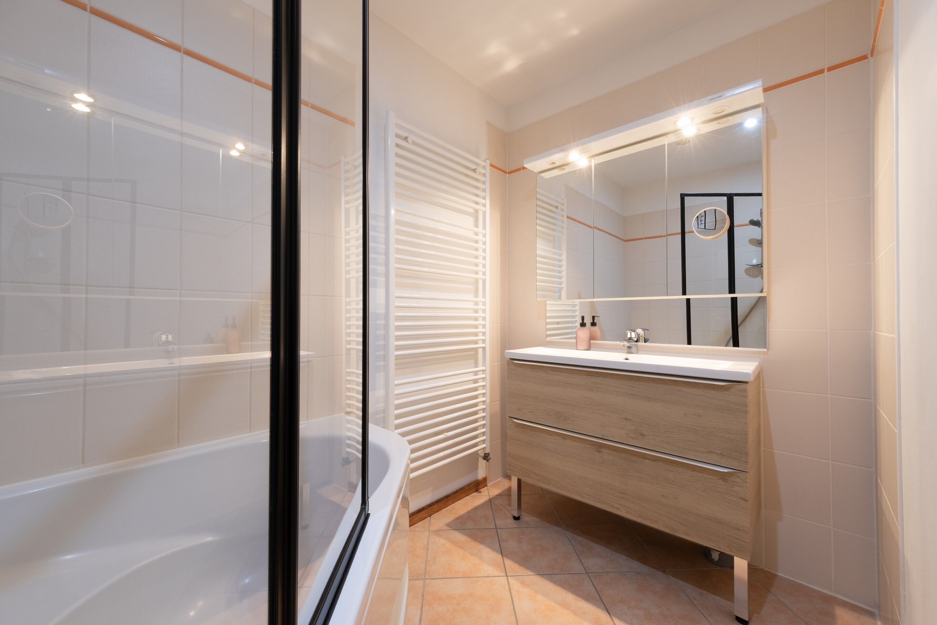 Un bagno moderno con una vasca, un mobile lavabo con specchio e uno spazio doccia.