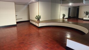 Un intérieur moderne avec un comptoir d’accueil incurvé, une plante en pot et un grand miroir qui reflète la pièce.