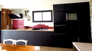 Una cocina moderna con gabinetes negros, un salpicadero de ladrillo rojo y una ventana sobre el fregadero.