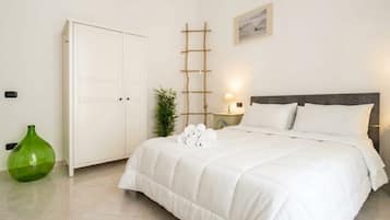 Ein Schlafzimmer mit einem Bett, einem Kleiderschrank, einem Nachttisch mit einer Lampe und einer grünen Vase.