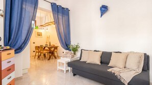 A modern living room with a sofa, a dining table, and blue curtains. - L\'onda del Mare - cozy sea-view balcony (Monopoli)