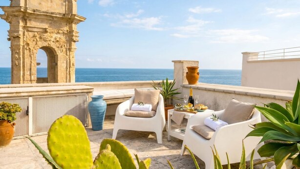 A terrace with white chairs, a table with food and drinks, a large vase, and a cactus plant. - L\'onda del Mare - cozy sea-view balcony (Monopoli)