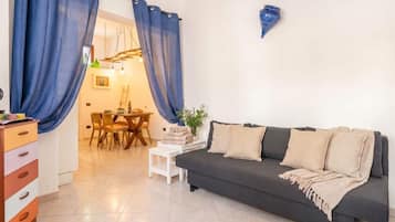 A living room with a sofa, a dining table with chairs, and a small white table.