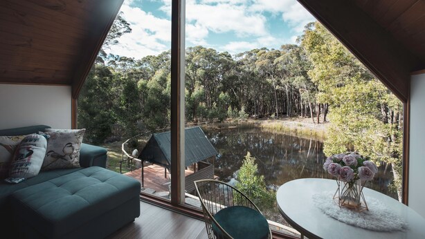 A modern interior with a large window overlooking a natural landscape, including a pond and forest. - La Moneta Retreat – A Sanctuary for Healing & Hope -Tranquil Hillside Haven (Dean)