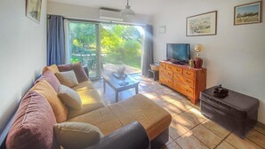 A living room with a sofa, a television, a wooden cabinet, and a small table. - Beautiful home in La Tour-d'Aigues with swimming pool (La Tour-d'Aigues)