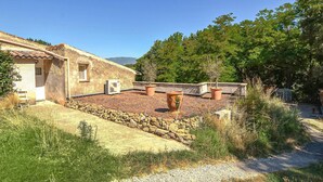 A rustic building with a tiled roof, stone walls, and a small window. There are potted plants and a gravel path leading to the entrance. - Beautiful home in La Tour-d'Aigues with swimming pool (La Tour-d'Aigues)