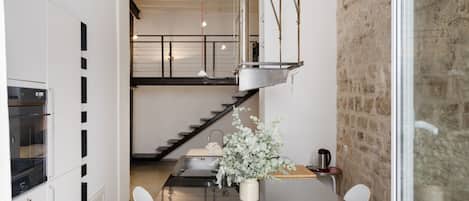 A modern kitchen with a central island, stainless steel appliances, and a hanging light fixture.