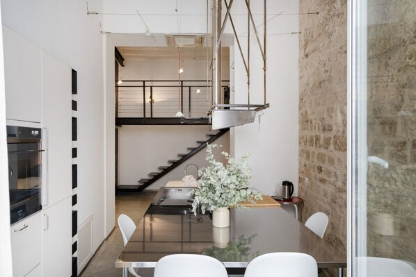 A modern kitchen with a central island, stainless steel appliances, and a hanging light fixture.