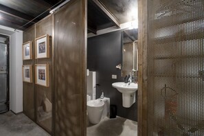 A modern bathroom with a large sink, bidet, and framed pictures on the wall.