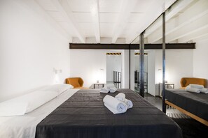 Una habitación de hotel moderna con una cama grande, un escritorio y una silla. Hay toallas sobre la cama y un espejo en la pared.