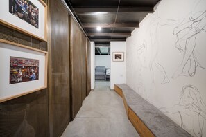 Un pasillo con obras de arte en las paredes, un banco y una escalera que conduce a otra habitación.